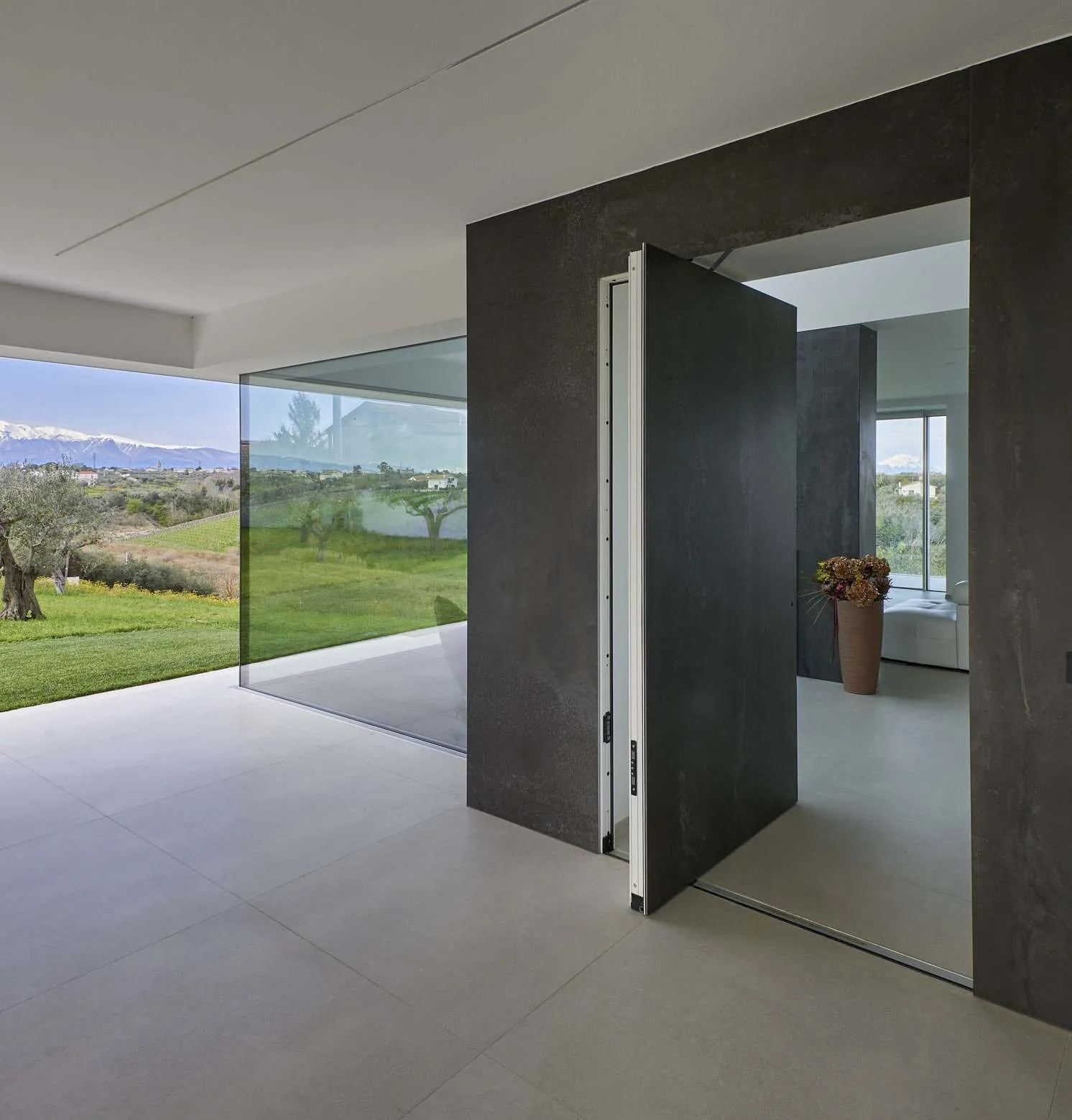 Large-format pivot door standing open inside a modern home