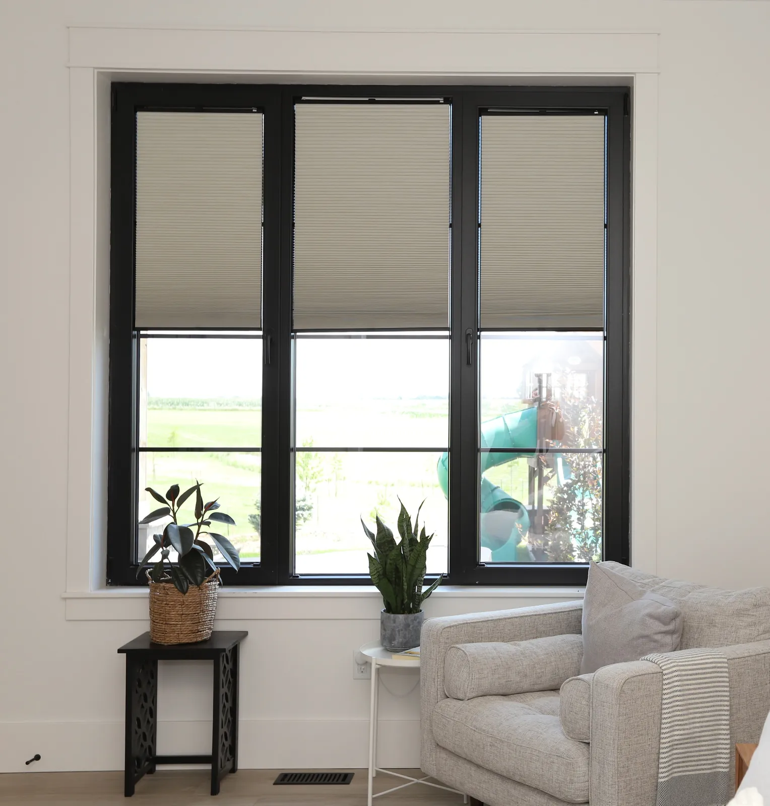 Black three-sash window with blinds in a living room with light walls
